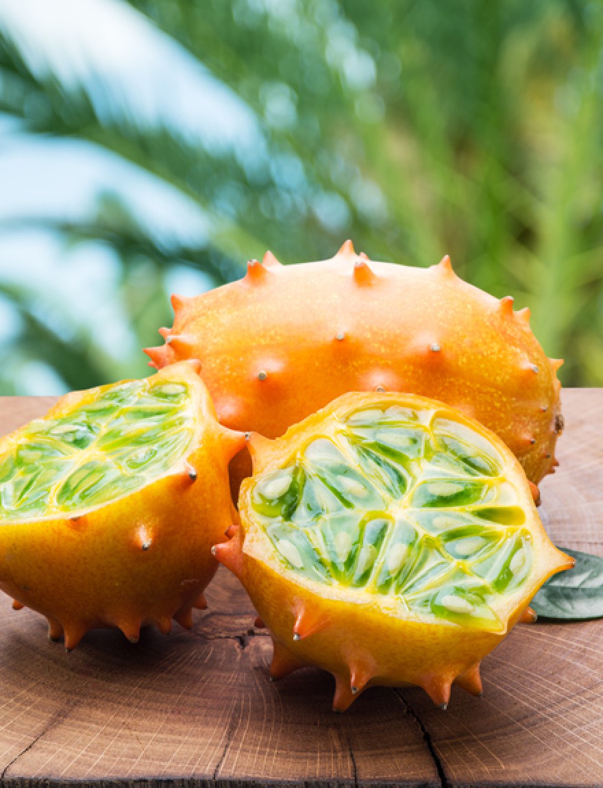 Kiwano fruits on the wooden table with green nature on the background.