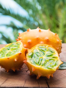 Kiwano fruits on the wooden table with green nature on the background.